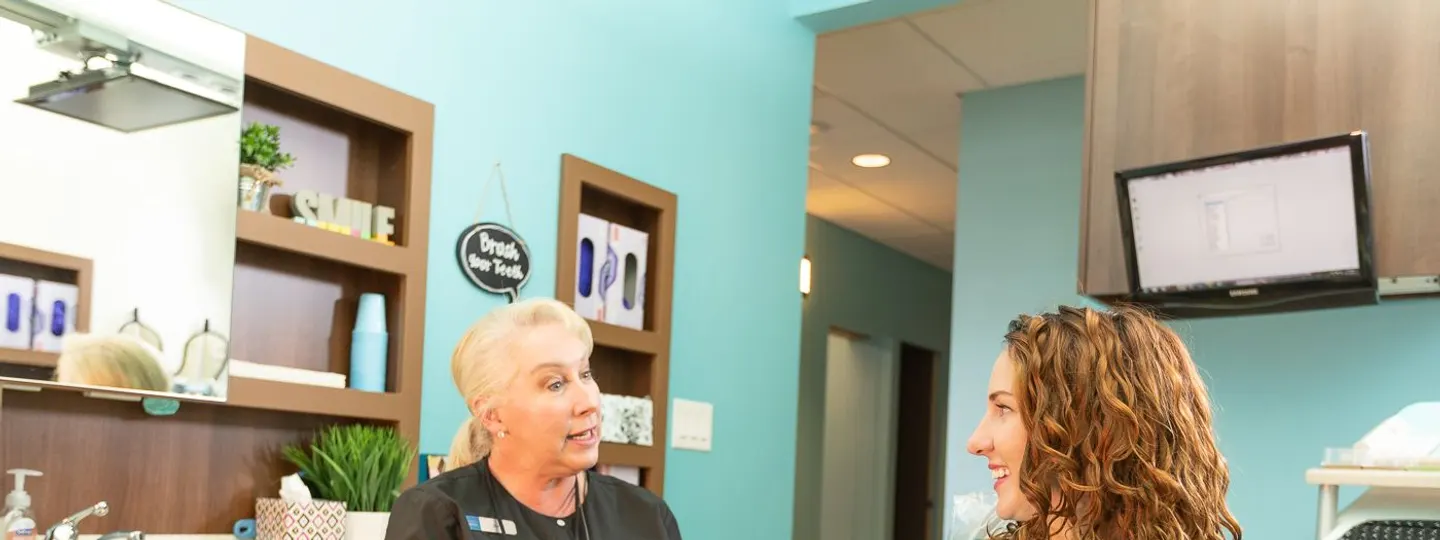 A Desert Ridge Dental hygienist talking with a patient in a treatment room