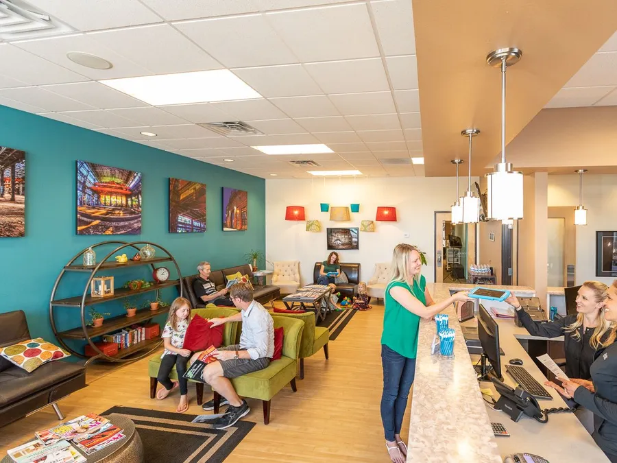 Families waiting in the colorful Desert Ridge Dental reception area while staff greet a patient at the front desk