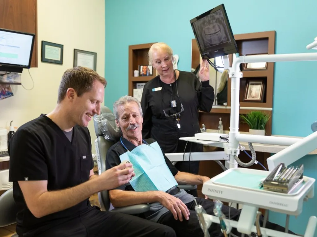 Dentist and assistant showing a patient their dental X-ray on screen at Desert Ridge Dental