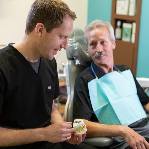 Dr. Mink showing model of teeth to dental patient.