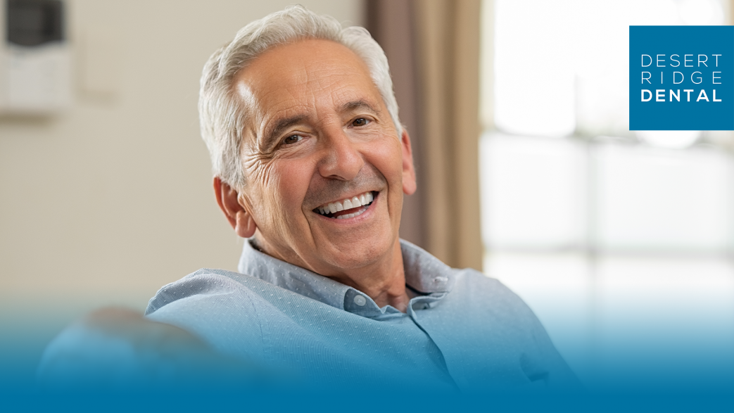 Elderly man sitting on couch, smiling.