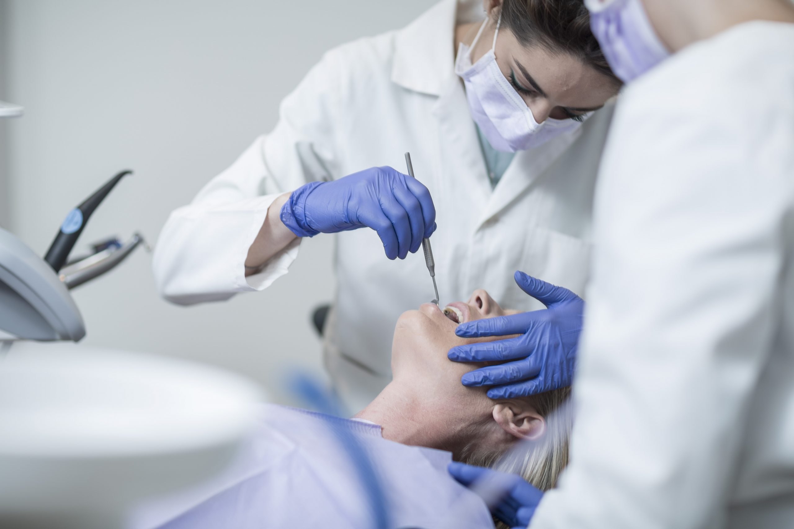 Female dentist examining patient with mouth mirror